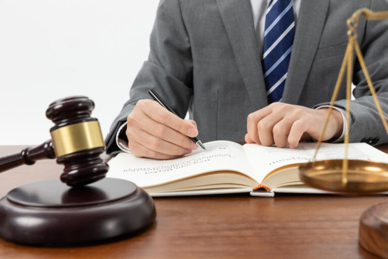 closeup-shot-person-writing-book-with-gavel-table (1)